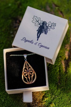 Bijoux en bois sculpté en forme de goutte et rappelant les ogives des cathédrales, les vitraux. Au centre se trouve une pierre noire en bois fossilisé.